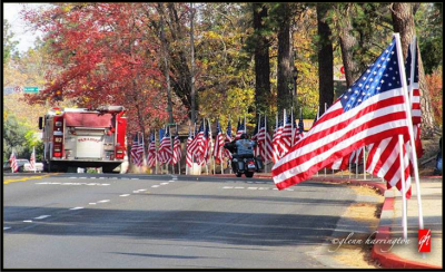 Skyway and Elliot Roads are lined with American flags as a fire truck drives alongside them