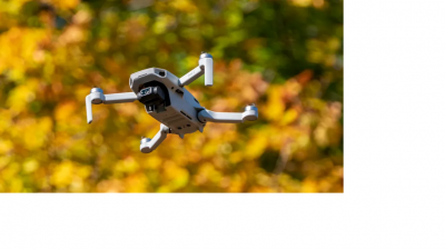 Photo of a drone flying with leaves behind it